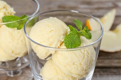 Photo of Scoops of melon sorbet and mint in glass dessert bowls on table, closeup