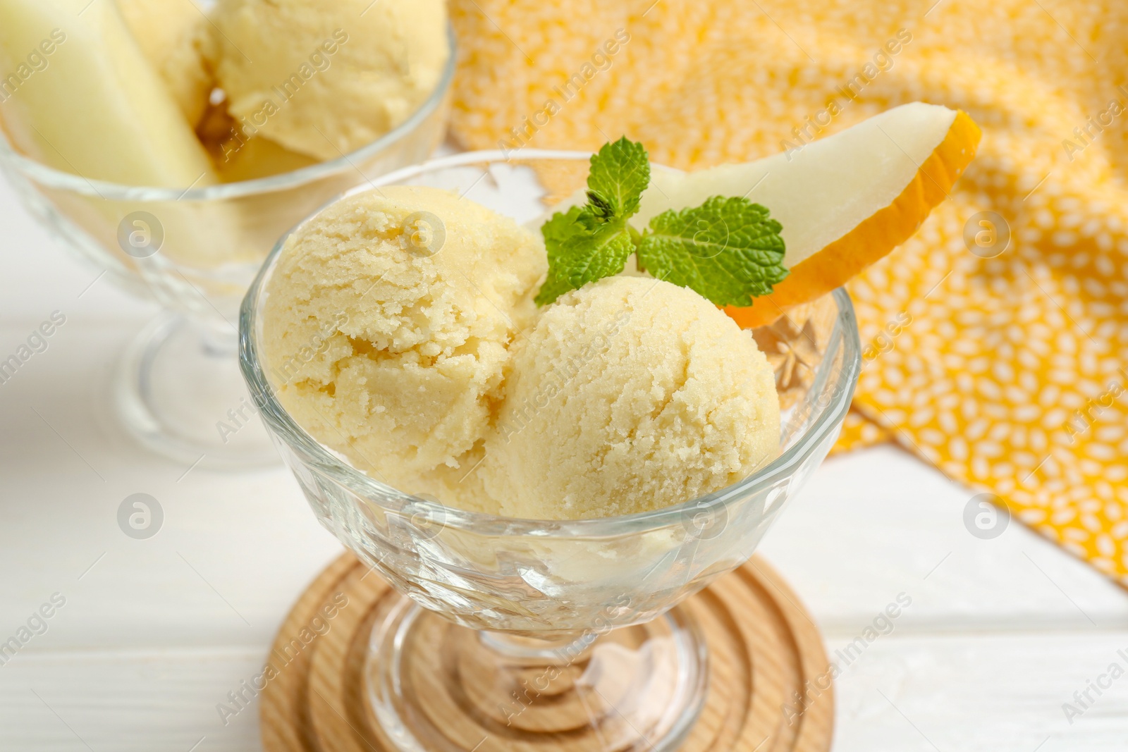 Photo of Scoops of melon sorbet with mint and fresh fruit in glass dessert bowls on white wooden table, closeup