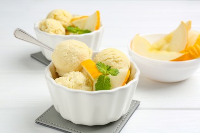 Photo of Scoops of melon sorbet with mint and fresh fruit in bowls on white wooden table, closeup