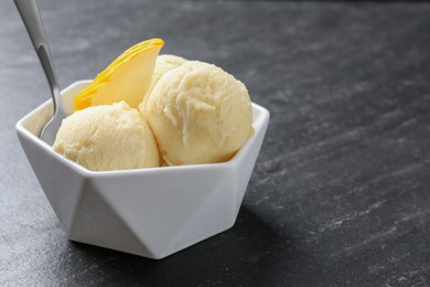 Photo of Scoops of tasty melon sorbet with fresh fruit and spoon in bowl on grey textured table, closeup. Space for text