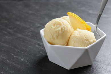 Photo of Scoops of tasty melon sorbet with fresh fruit and spoon in bowl on grey textured table, closeup. Space for text