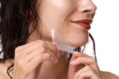 Woman peeling off face mask on white background, closeup