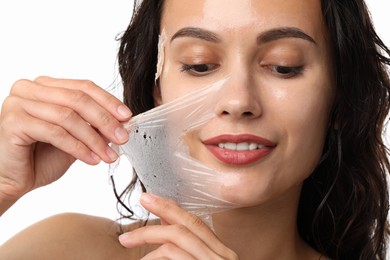 Photo of Smiling woman peeling off face mask on white background, closeup