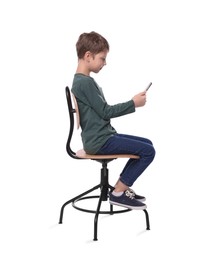 Boy with correct posture and phone sitting on chair against white background