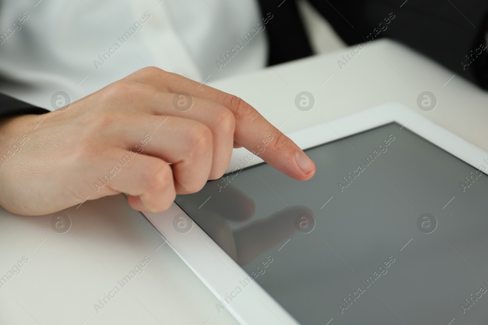 Photo of Businesswoman using tablet at white table indoors, closeup. Modern technology