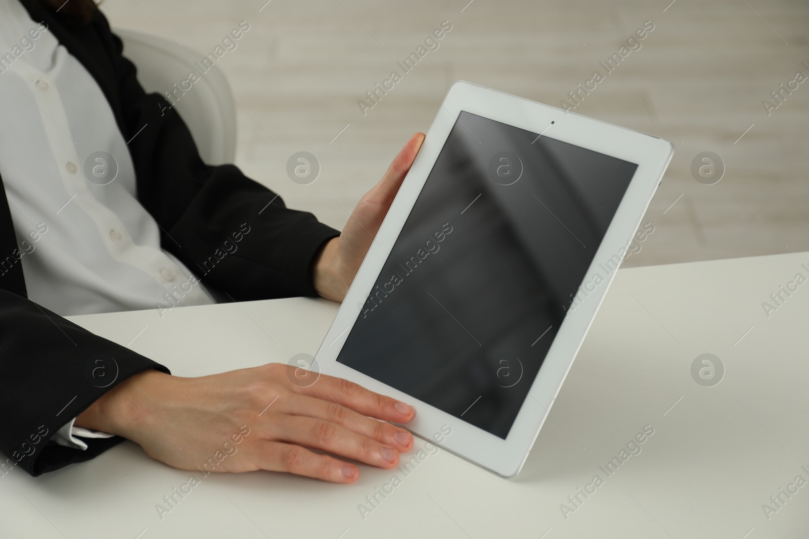 Photo of Businesswoman using tablet at white table indoors, closeup. Modern technology