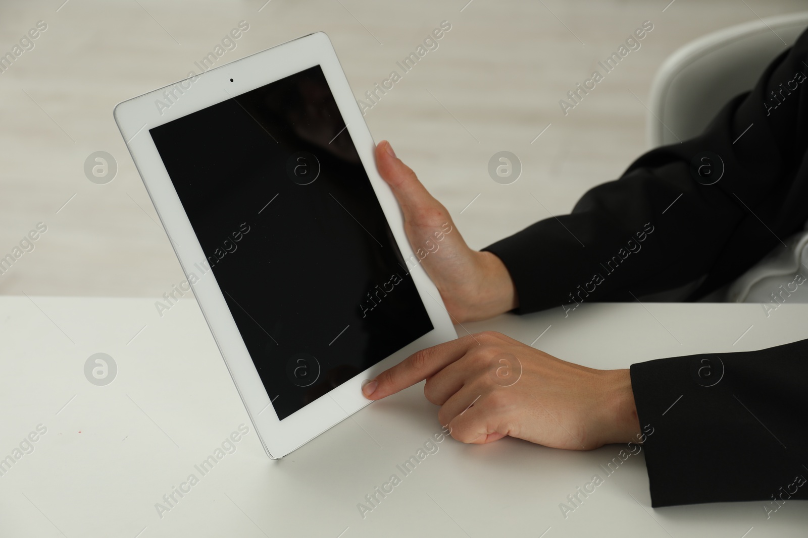 Photo of Businesswoman using tablet at white table indoors, closeup. Modern technology