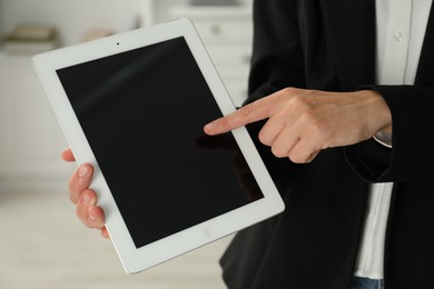 Photo of Businesswoman using tablet indoors, closeup. Modern technology