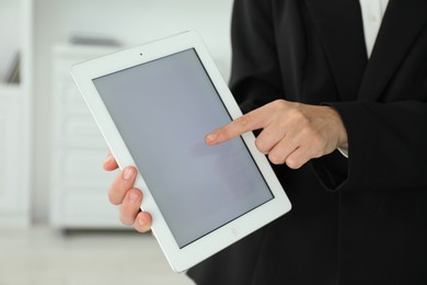 Photo of Businesswoman using tablet indoors, closeup. Modern technology