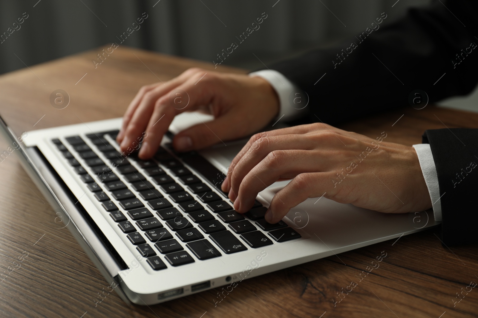 Photo of Businesswoman using laptop at wooden table indoors, closeup. Modern technology