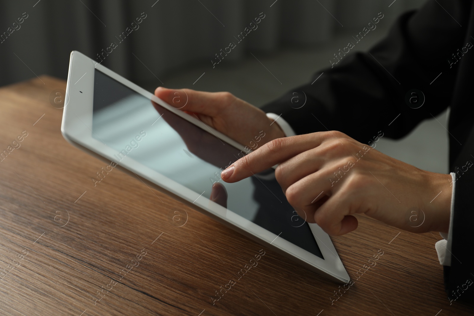 Photo of Businesswoman using tablet at wooden table indoors, closeup. Modern technology