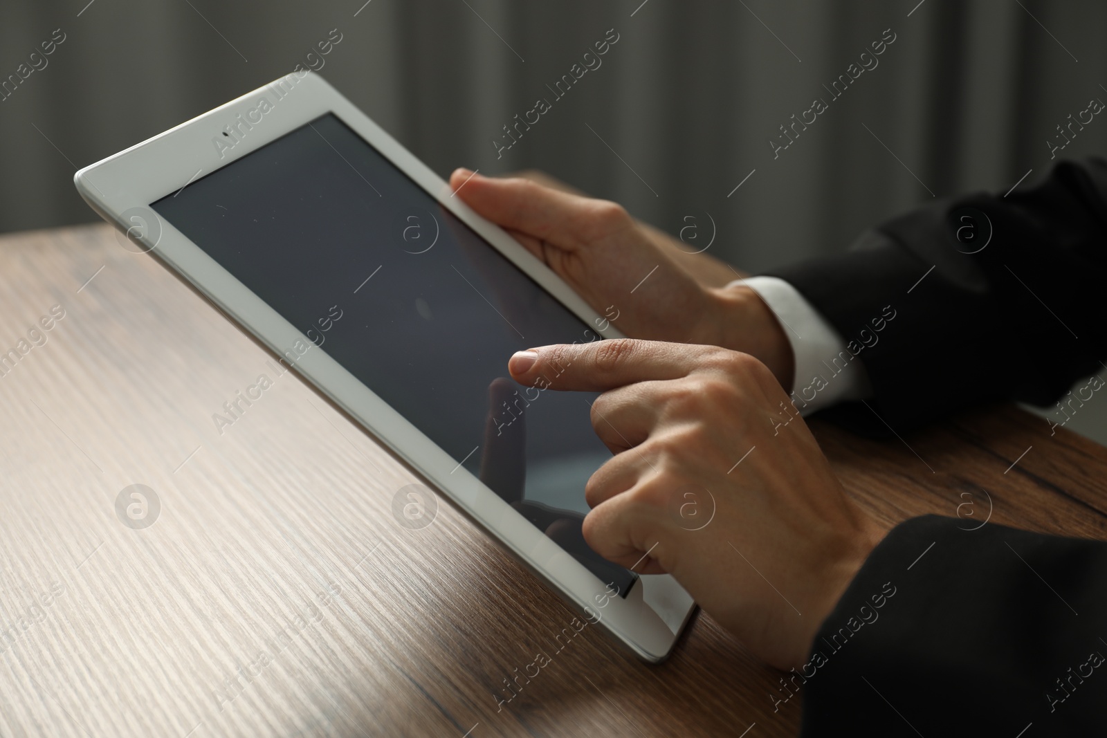 Photo of Businesswoman using tablet at wooden table indoors, closeup. Modern technology