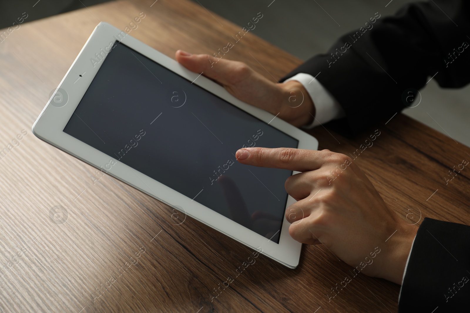 Photo of Businesswoman using tablet at wooden table indoors, closeup. Modern technology