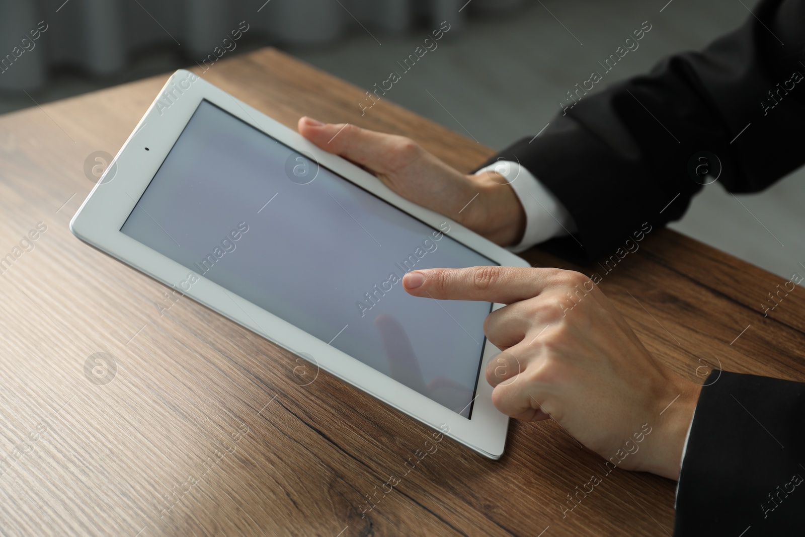 Photo of Businesswoman using tablet at wooden table indoors, closeup. Modern technology