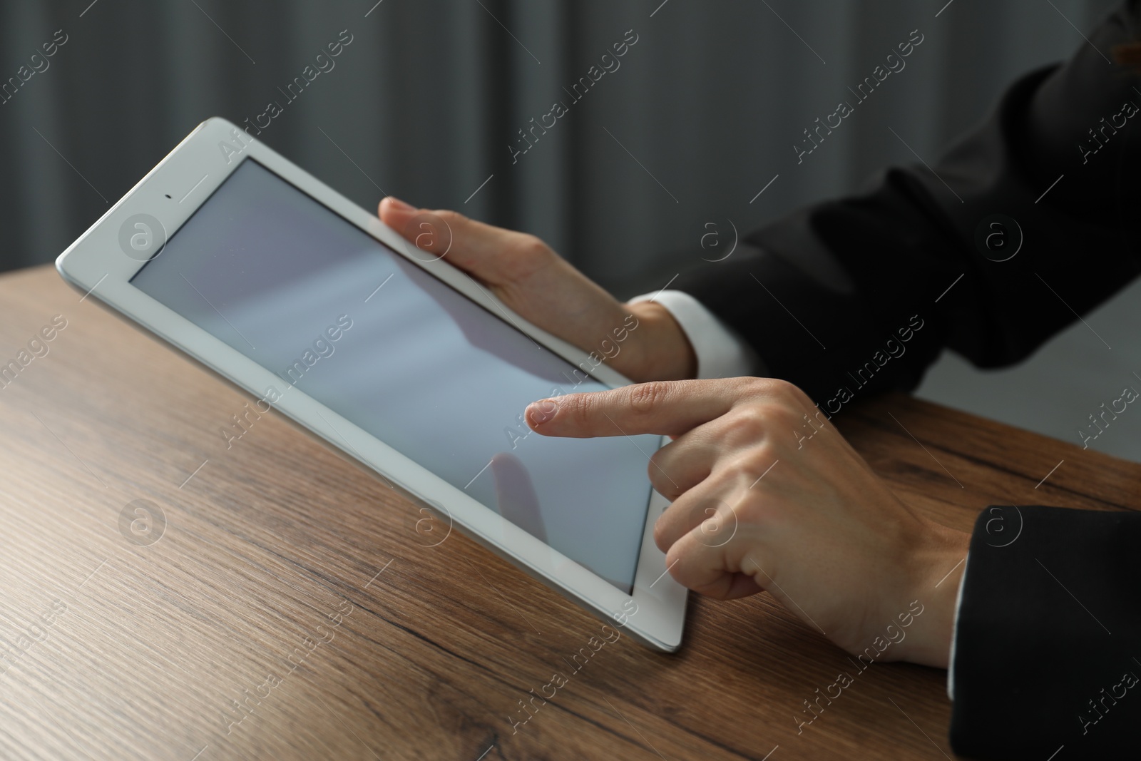 Photo of Businesswoman using tablet at wooden table indoors, closeup. Modern technology