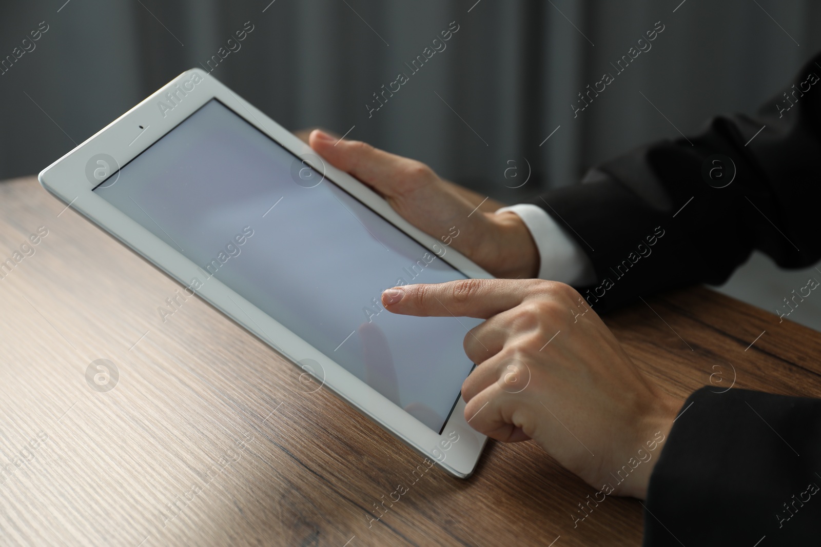 Photo of Businesswoman using tablet at wooden table indoors, closeup. Modern technology