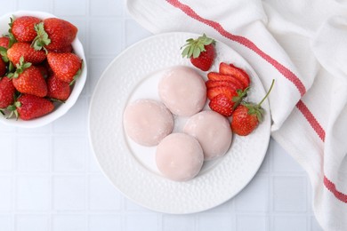 Delicious mochi and strawberries on white tiled table, top view