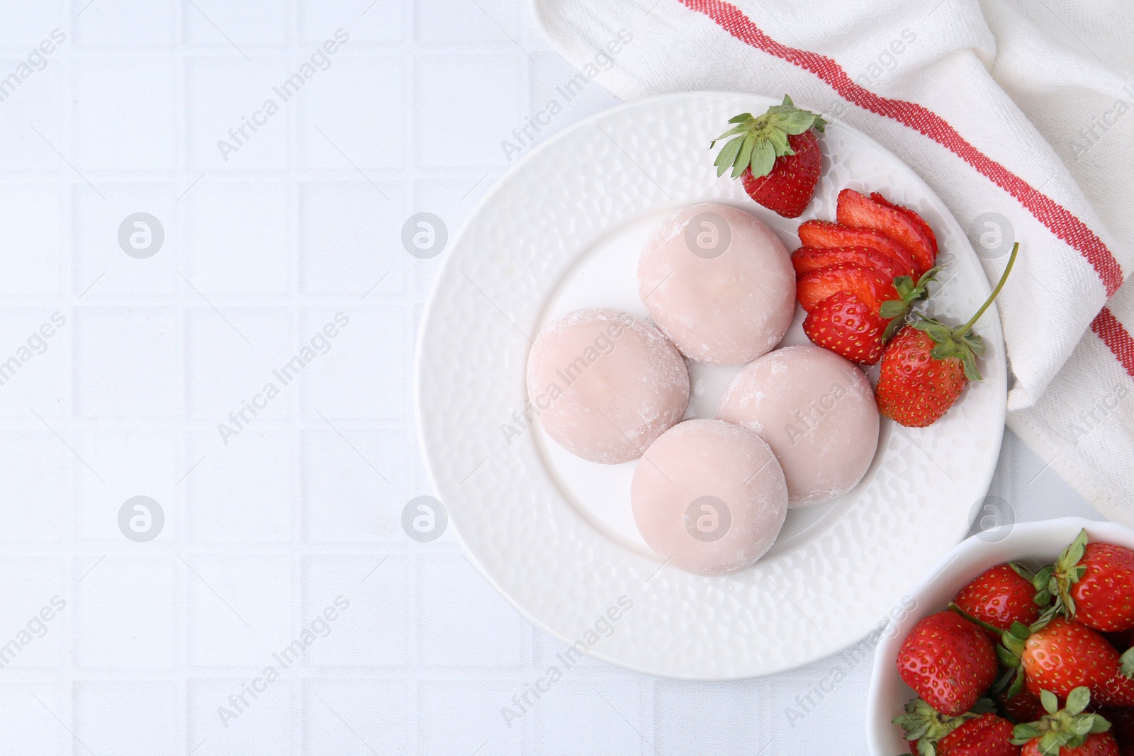 Photo of Delicious mochi and strawberries on white tiled table, top view. Space for text