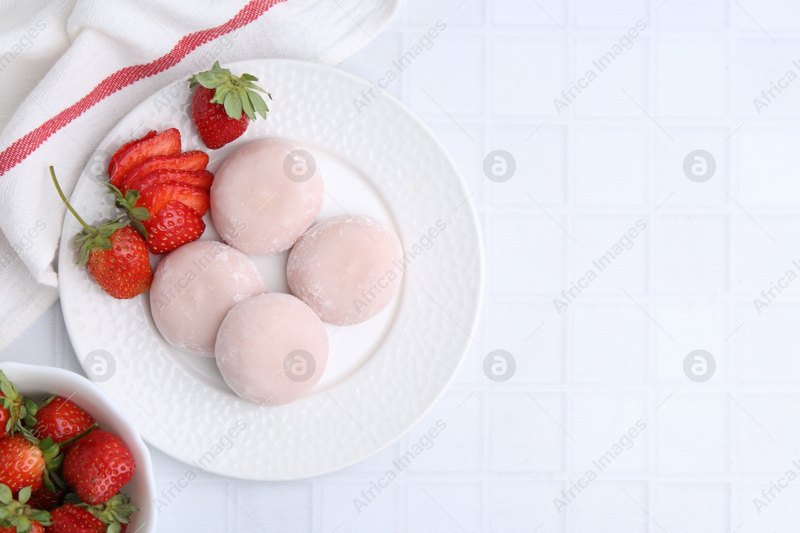 Photo of Delicious mochi and strawberries on white tiled table, top view. Space for text