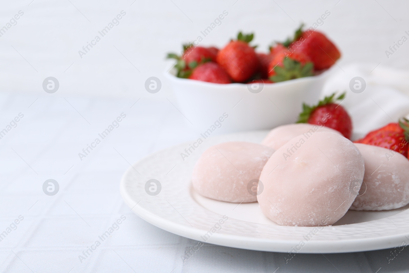 Photo of Delicious mochi and strawberries on white tiled table, closeup