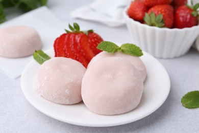 Photo of Delicious mochi, strawberries and mint on light grey table, closeup