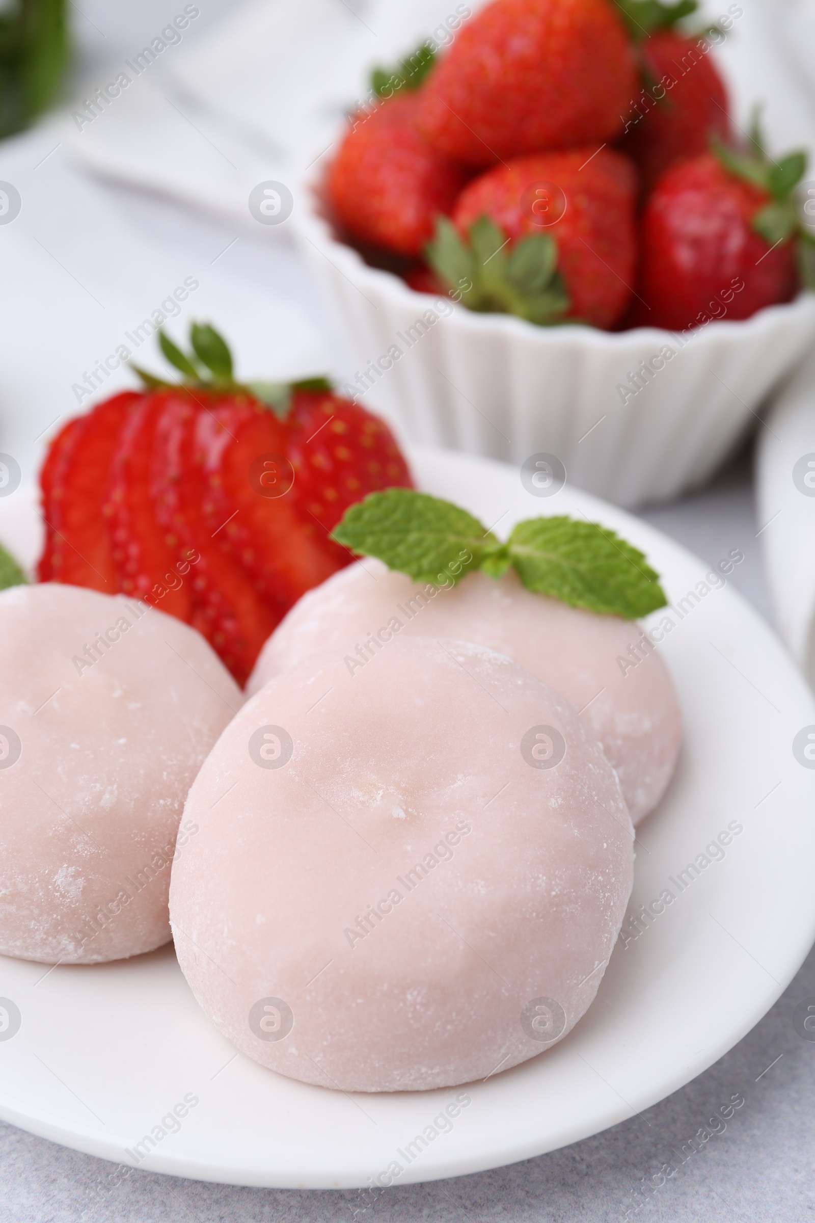 Photo of Delicious mochi, strawberries and mint on light grey table, closeup