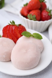 Delicious mochi, strawberries and mint on light grey table, closeup