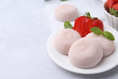 Delicious mochi, strawberries and mint on light grey table, closeup. Space for text