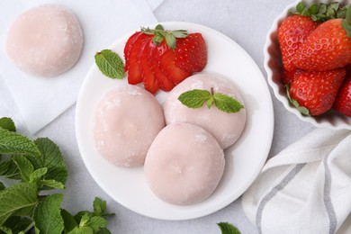 Photo of Delicious mochi, strawberries and mint on light grey table, top view