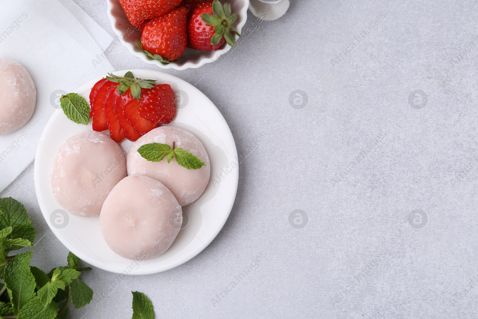 Photo of Delicious mochi, strawberries and mint on light grey table, top view. Space for text