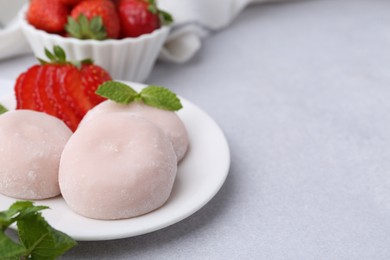 Delicious mochi, strawberries and mint on light grey table, closeup. Space for text