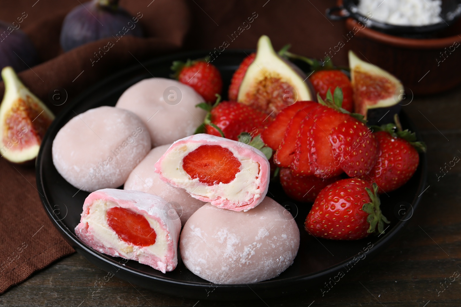 Photo of Delicious mochi with strawberries and figs on wooden table, closeup