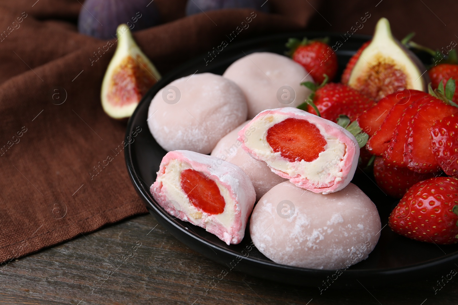 Photo of Delicious mochi with strawberries and figs on wooden table, closeup