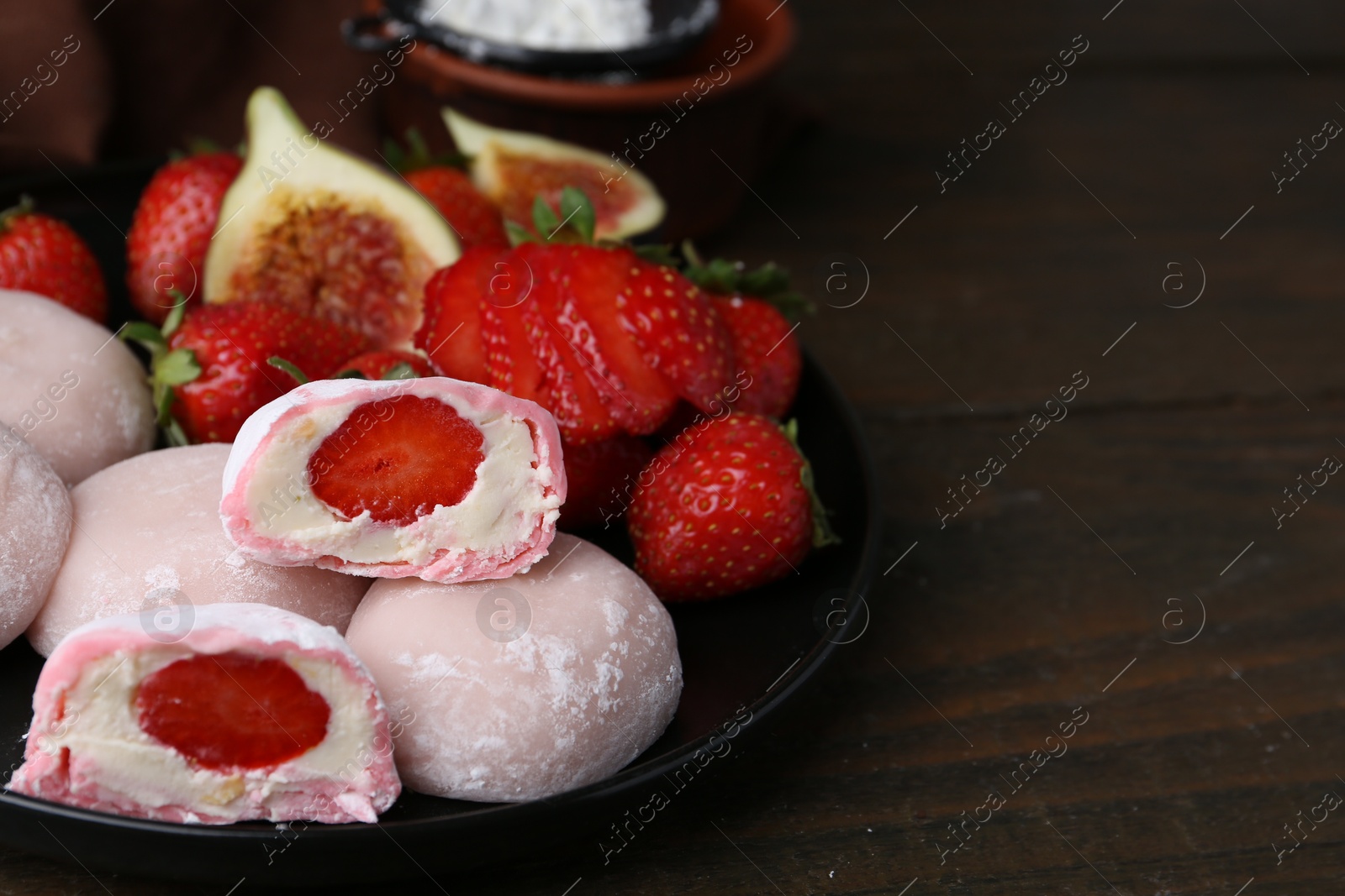 Photo of Delicious mochi with strawberries and figs on wooden table, closeup