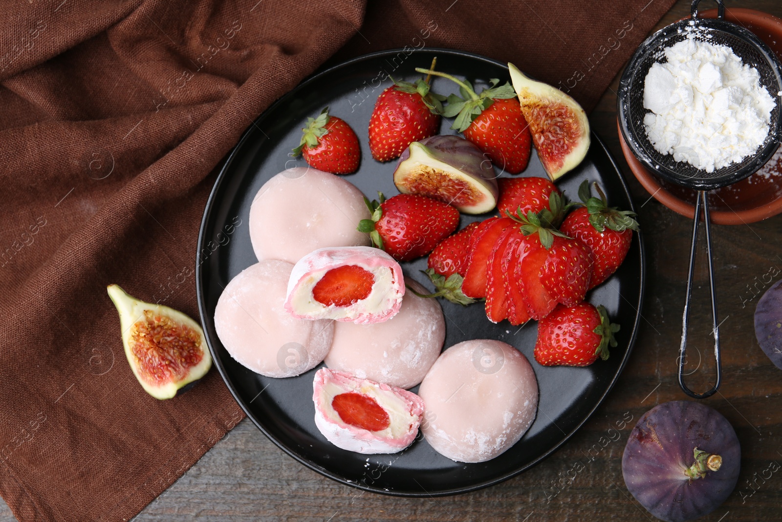 Photo of Delicious mochi with strawberries, figs and flour on wooden table, top view