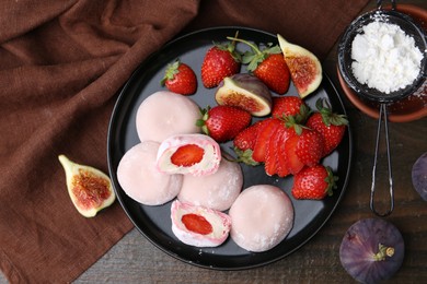 Delicious mochi with strawberries, figs and flour on wooden table, top view