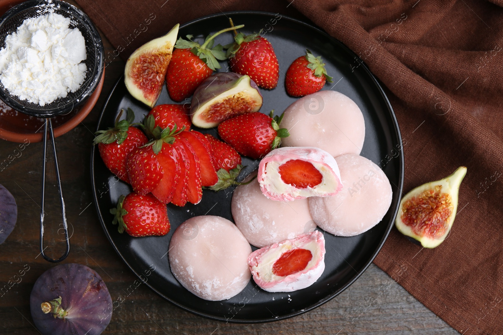 Photo of Delicious mochi with strawberries, figs and flour on wooden table, top view