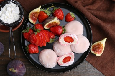 Photo of Delicious mochi with strawberries, figs and flour on wooden table, top view