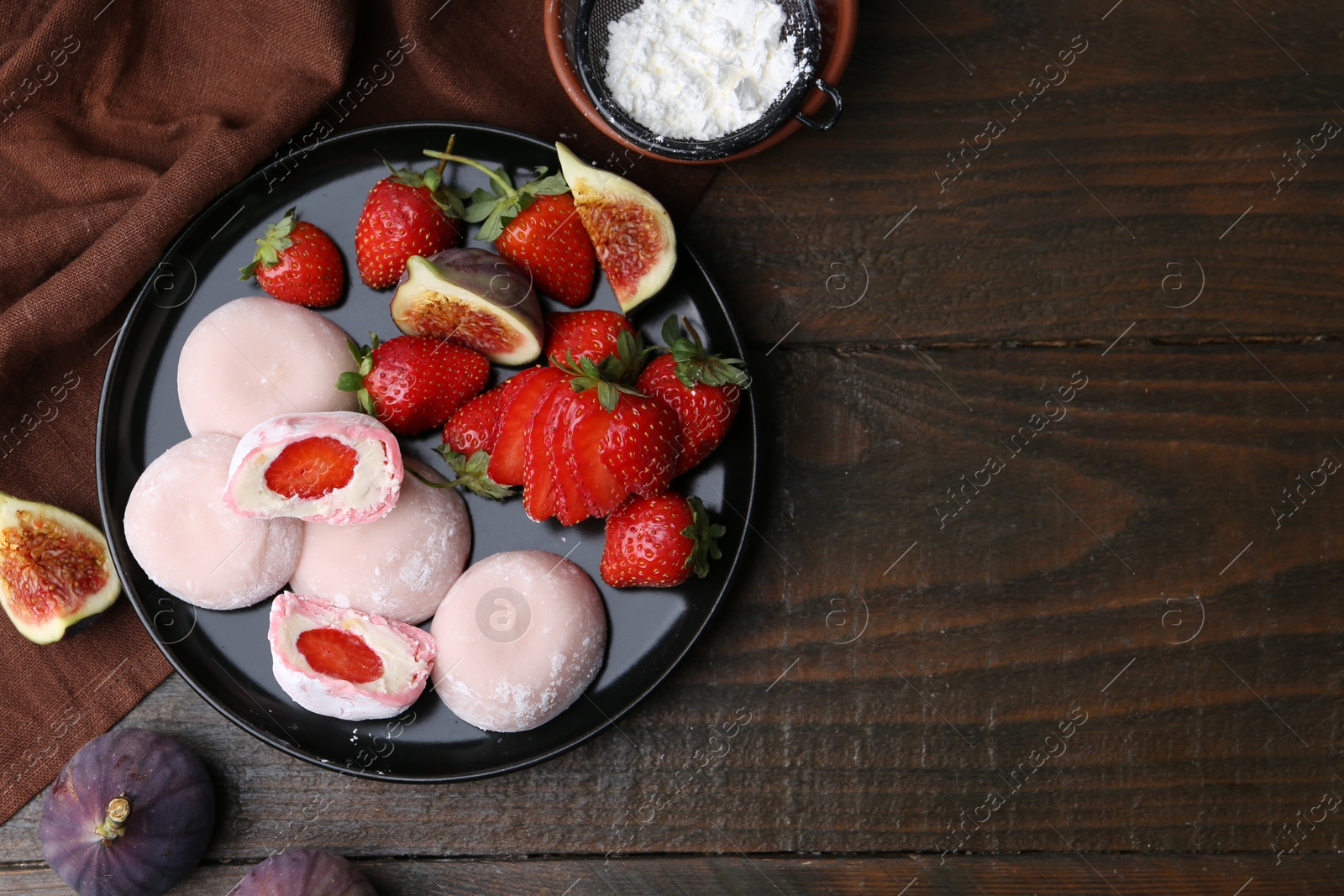 Photo of Delicious mochi with strawberries, figs and flour on wooden table, top view. Space for text