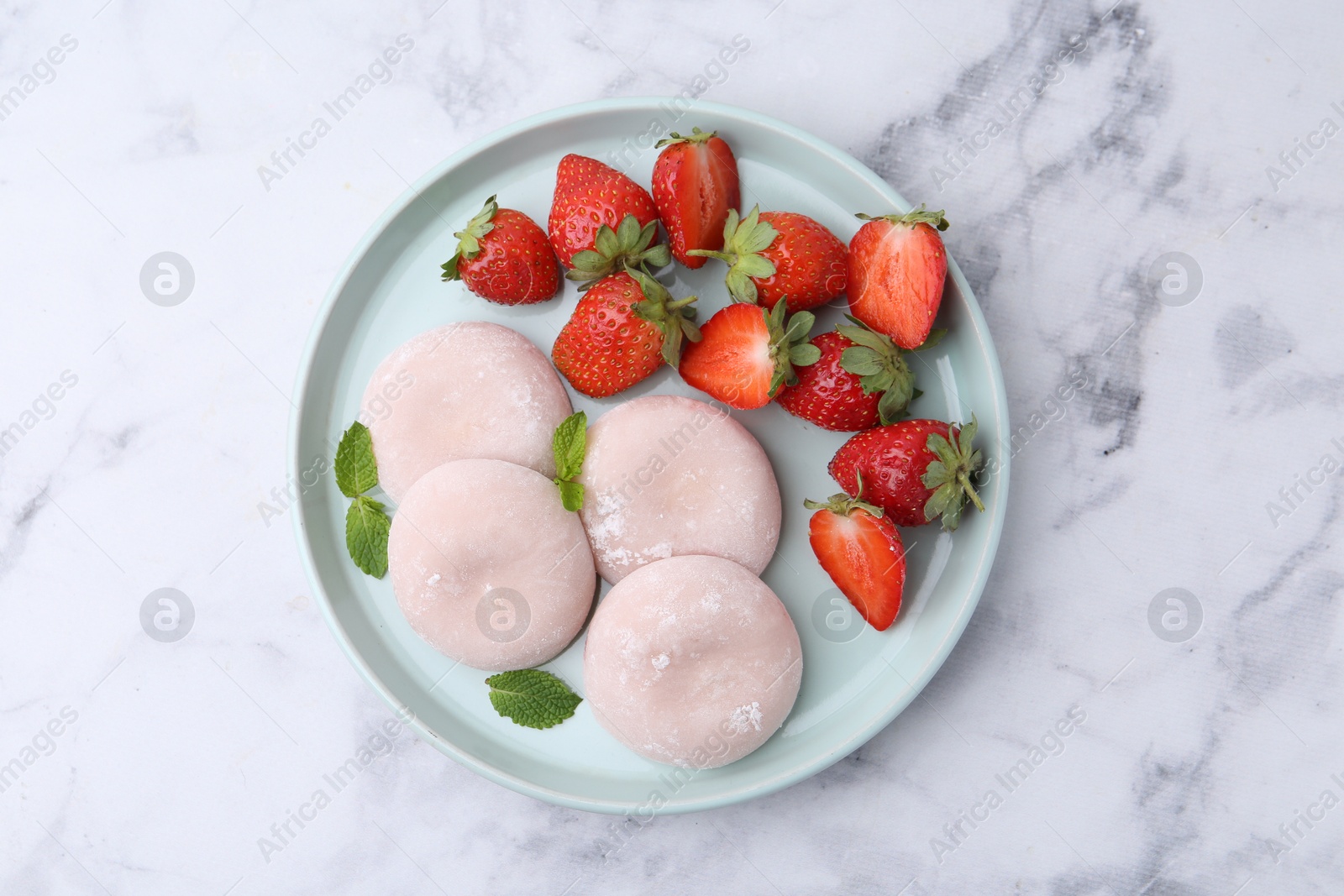 Photo of Delicious mochi, strawberries and mint on white marble table, top view