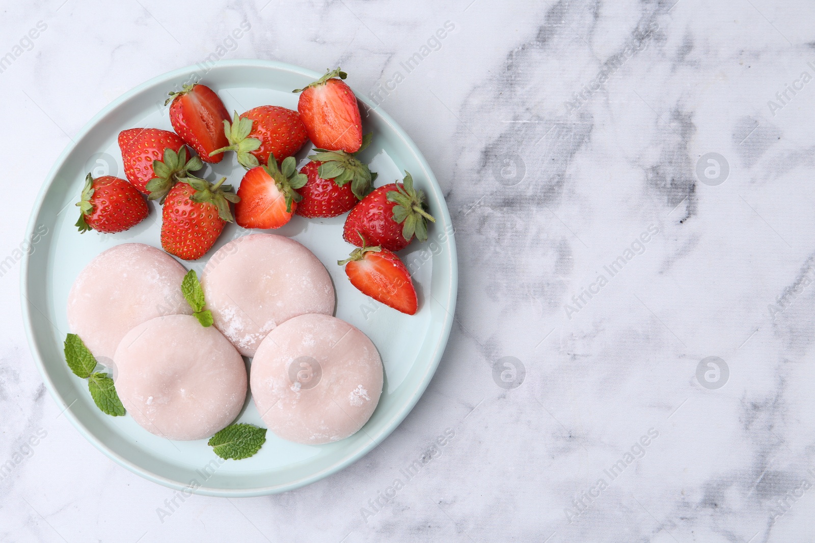 Photo of Delicious mochi, strawberries and mint on white marble table, top view. Space for text