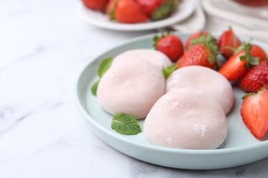 Photo of Delicious mochi, strawberries and mint on white marble table, closeup