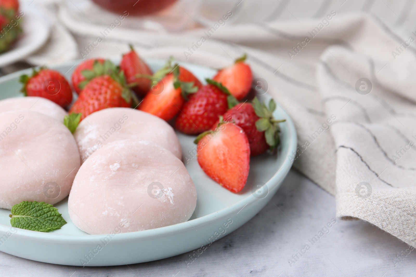 Photo of Delicious mochi, strawberries and mint on white marble table, closeup