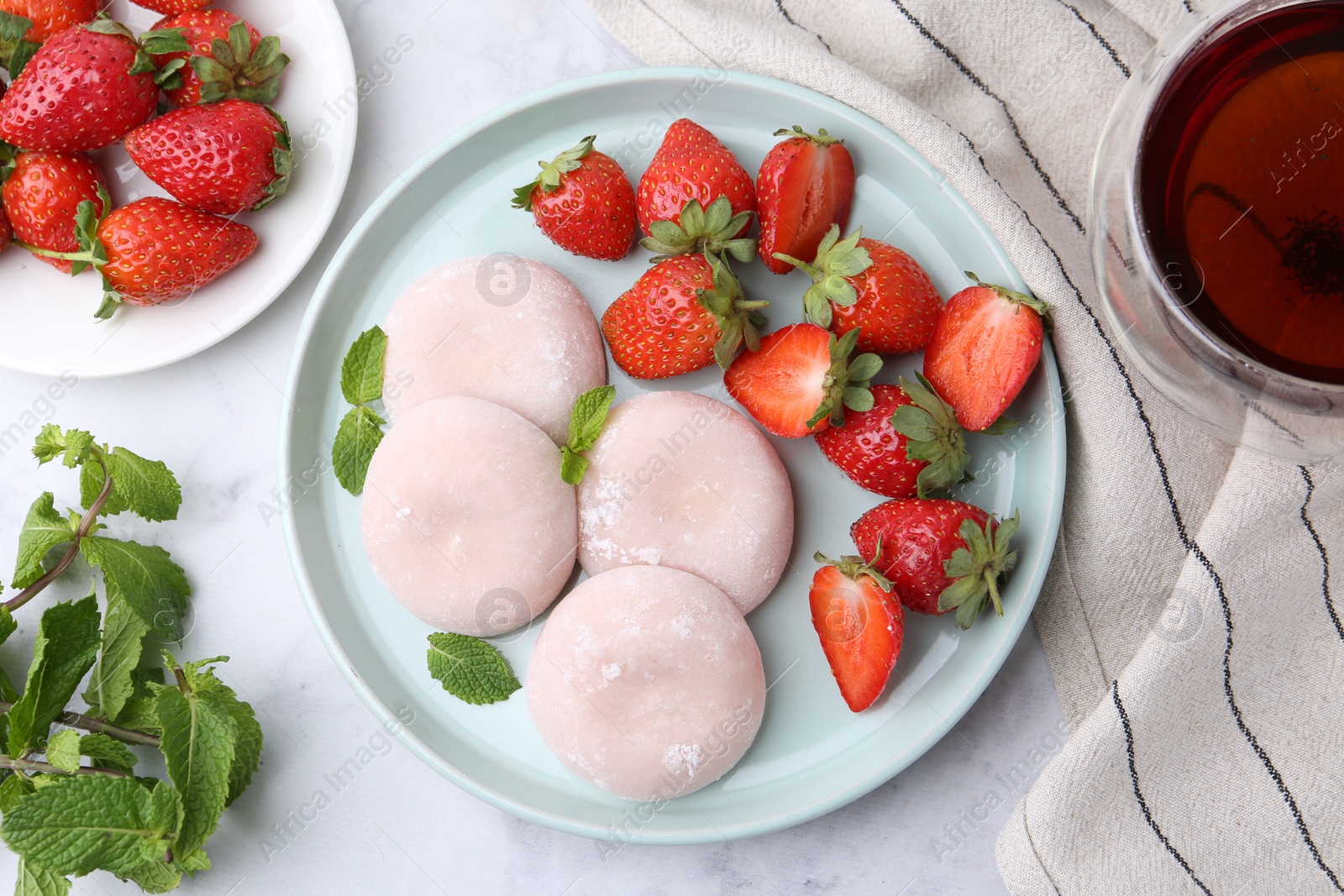 Photo of Delicious mochi with strawberries, mint and tea on white marble table, top view