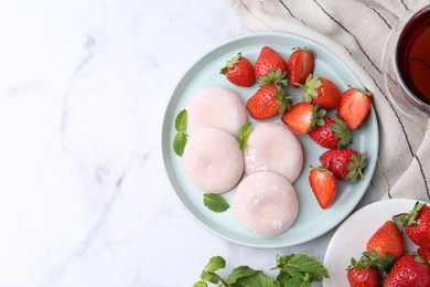 Photo of Delicious mochi with strawberries and mint on white marble table, top view. Space for text