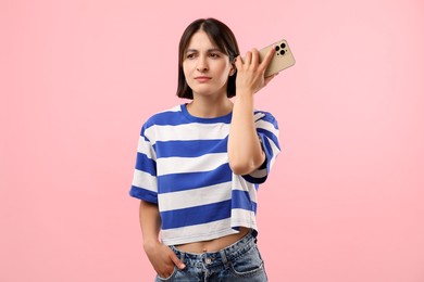 Photo of Beautiful woman with smartphone listening to voice message on pink background