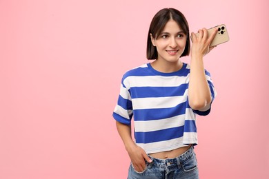 Photo of Beautiful woman with smartphone listening to voice message on pink background, space for text