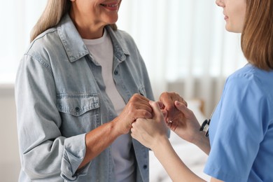 Young healthcare worker supporting senior patient indoors, closeup