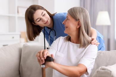 Photo of Smiling healthcare worker supporting senior patient indoors