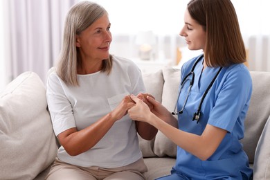 Young healthcare worker supporting senior patient indoors